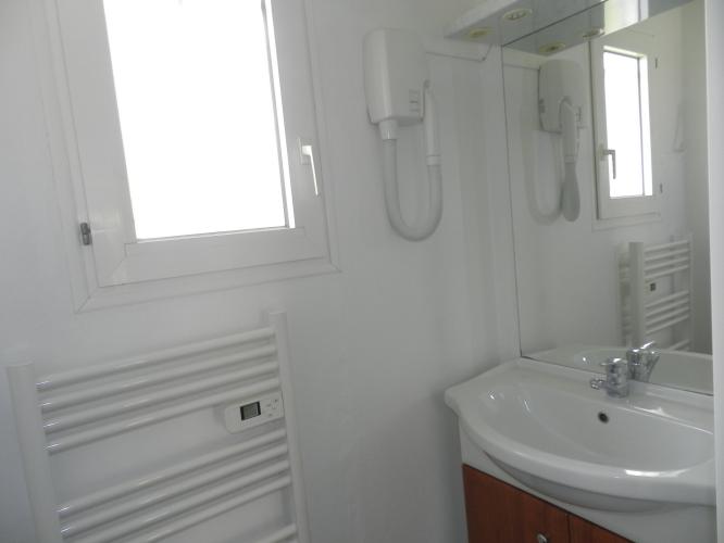 La salle de bain avec lavabo, seche cheveux mural  et douche